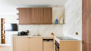 Eine moderne Küche mit Holzausstattung, einer Marmor-Spritzschutzwand und einem integriertem Geschirrspüler.