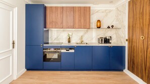 Una cucina moderna con mobili blu, un pensile in legno, uno schienale in marmo e una porta in legno.