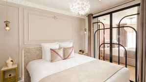 Una camera d'albergo con un letto grande, un comodino, un pannello decorativo e vista attraverso una porta in vetro.