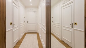 Un corridoio con porte bianche, pavimento in legno e una colonna centrale.