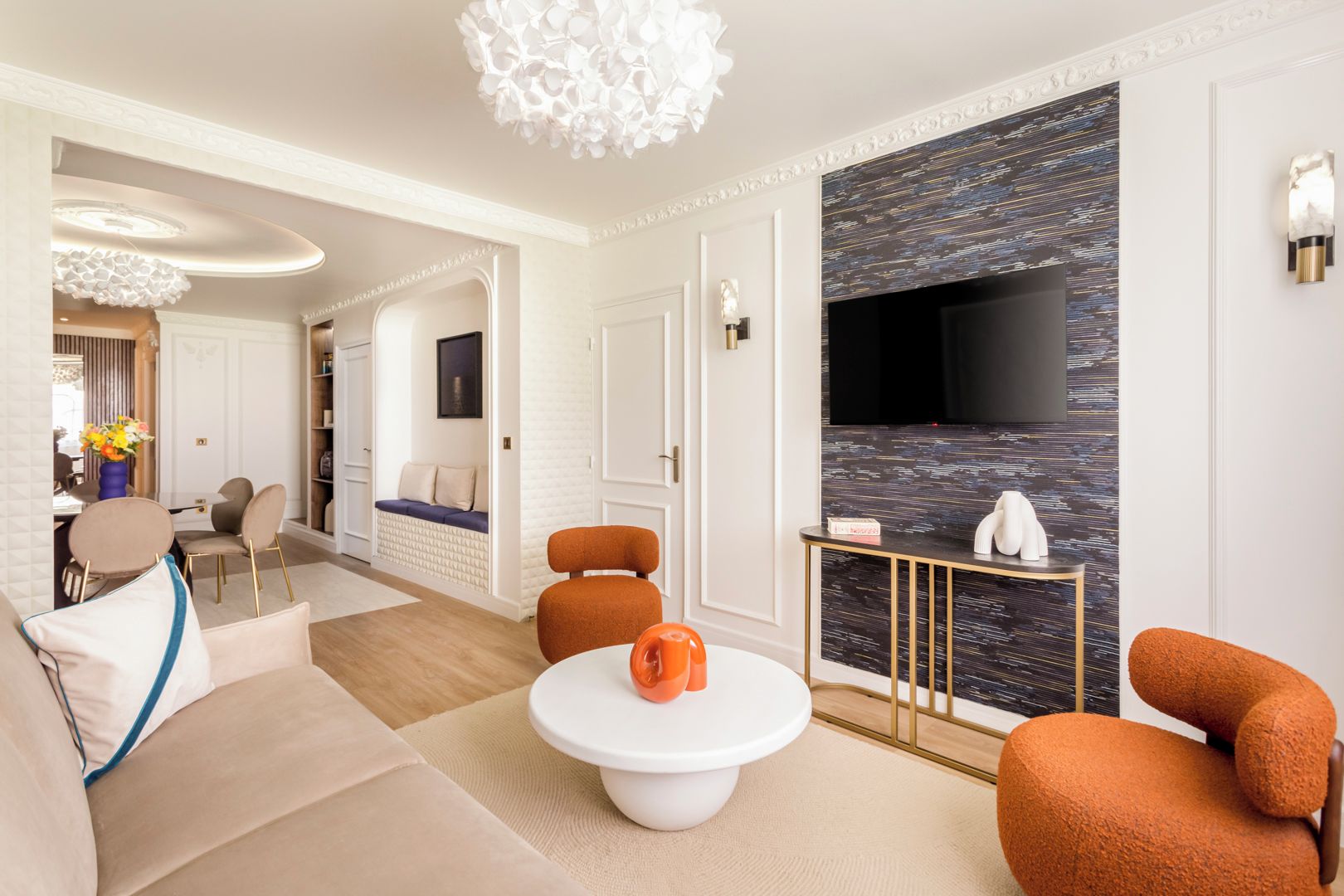 A modern living room with a sofa, armchairs, a coffee table, and a TV mounted on a textured wall.