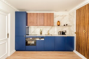 Eine moderne Küche mit blauen Schränken, einem Holzboden darüber, einer Marmor-Spritzschutzwand und einer Holztür.