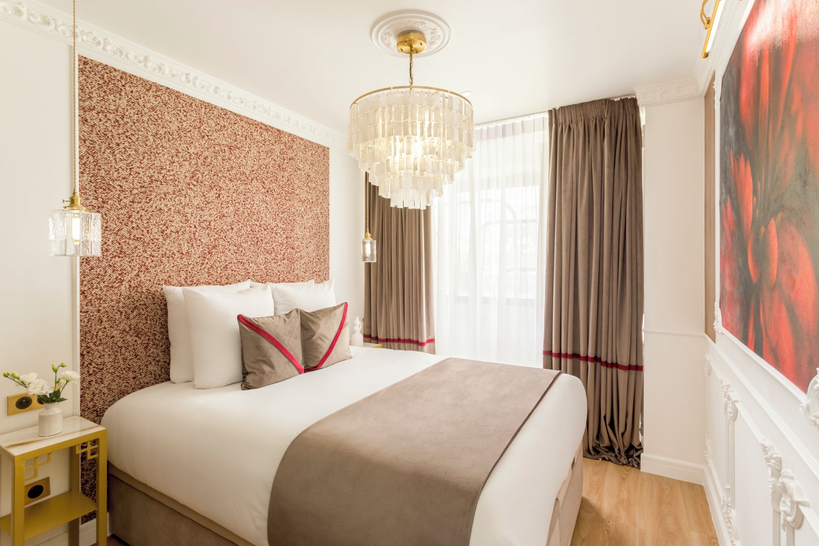 Una habitación de hotel con una cama grande, un muro decorativo, una araña y un cuadro.