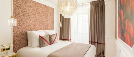 Una habitación de hotel con una cama grande, un muro decorativo, una araña y un cuadro.