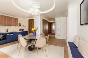 Eine moderne Küche mit blauen Schränken, einer Marmorarbeitsplatte und einem Essbereich mit rundem Tisch und Stühlen.