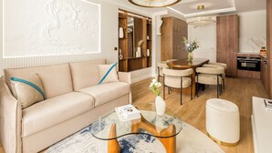 Una sala de estar moderna con un sofá color beige, una mesa de centro de vidrio y una zona de comedor con una mesa y sillas de madera.
