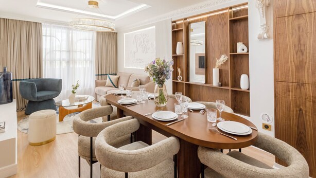 Un comedor moderno con una larga mesa de madera dispuesta para seis personas, rodeada de sillas tapizadas.