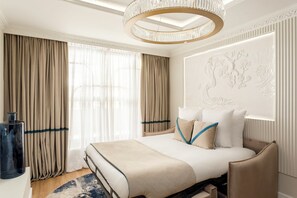 Una habitación de hotel moderna con una cama grande, una araña y un panel decorativo en la pared.
