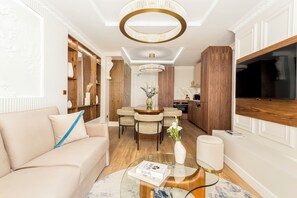 A modern living room with a sofa, a glass coffee table, and a dining area with a wooden table and chairs.