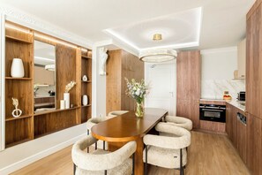 A modern kitchen with wooden cabinetry, a marble countertop, and a built-in oven. - Merveil - Luxury Suite - Marais - Lenoir III (Paris)
