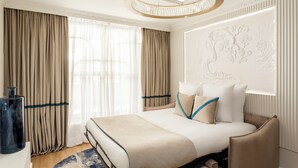 Una habitación de hotel moderna con una cama grande, una araña y un panel decorativo en la pared.