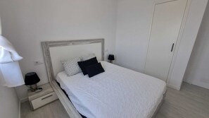 Un dormitorio con cama, lámparas de noche, mesita de noche y armario.