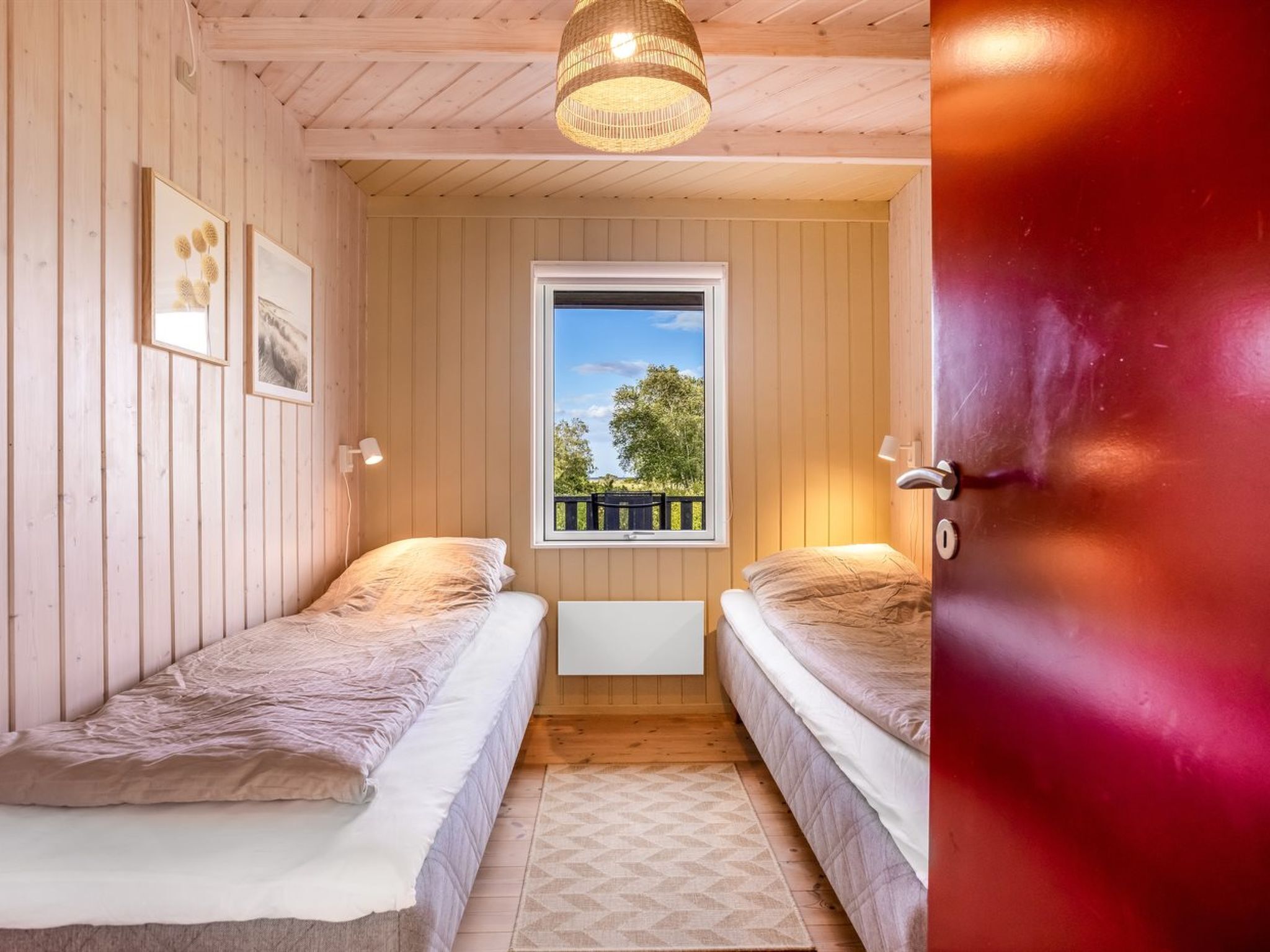 Una habitación pequeña y acogedora con dos camas individuales, un ventanal con vistas a la vegetación y techo de madera.