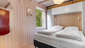 Un dormitorio con cama, espejo, ventana y una lámpara colgante.