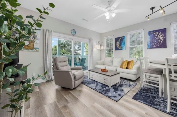 A modern living room with a sofa, armchair, coffee table, and dining area.