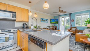 A modern kitchen with a central island, built-in appliances, and a dining area with a view to the outdoors. - Summer Blowout-Avail dates on Sale - Vacation at Ko Olina Hillside Villa 1498-8 (Kapolei)