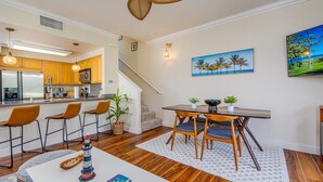 A modern kitchen with wooden cabinets, stainless steel appliances, and a bar area with stools. - Summer Blowout-Avail dates on Sale - Vacation at Ko Olina Hillside Villa 1498-8 (Kapolei)