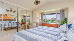A bedroom with a large bed, a chair, a dresser, and a window with a view of trees. - Summer Blowout-Avail dates on Sale - Vacation at Ko Olina Hillside Villa 1498-8 (Kapolei)