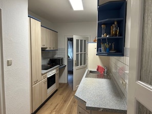 A compact kitchen with a microwave, oven, and granite countertop.