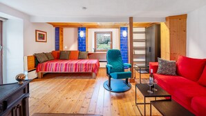 A bedroom with a bed, a red sofa, a blue chair, and a small table with wine glasses. - Apartment 'Ferienwohnung Karleidoskope' with Private Terrace, Private Garden and Wi-Fi (Buhlenberg)