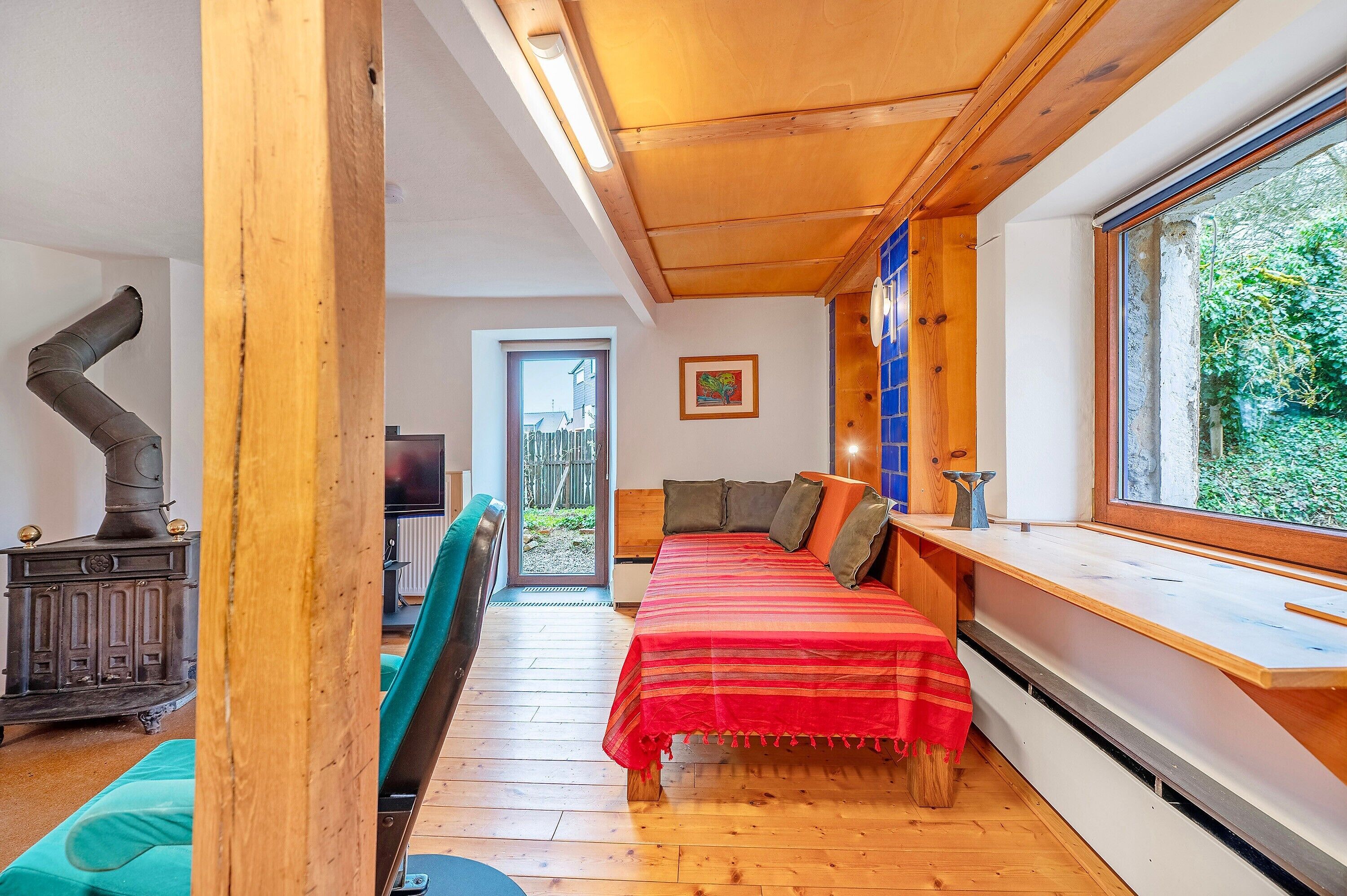 A room with a bed, a window, a wooden ceiling, and a radiator.