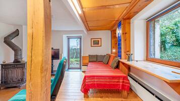 A room with a bed, a window, a wooden ceiling, and a radiator.