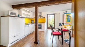 A modern kitchen with white cabinets, a wooden beam ceiling, and a dining area with red chairs. - Apartment 'Ferienwohnung Karleidoskope' with Private Terrace, Private Garden and Wi-Fi (Buhlenberg)