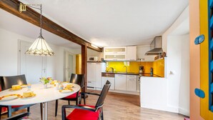 A dining area with a round table, chairs, and a hanging light fixture. - Apartment 'Ferienwohnung Karleidoskope' with Private Terrace, Private Garden and Wi-Fi (Buhlenberg)