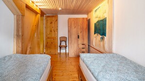 A bedroom with two beds, wooden walls, a chair, and a painting on the wall. - Apartment 'Ferienwohnung Karleidoskope' with Private Terrace, Private Garden and Wi-Fi (Buhlenberg)