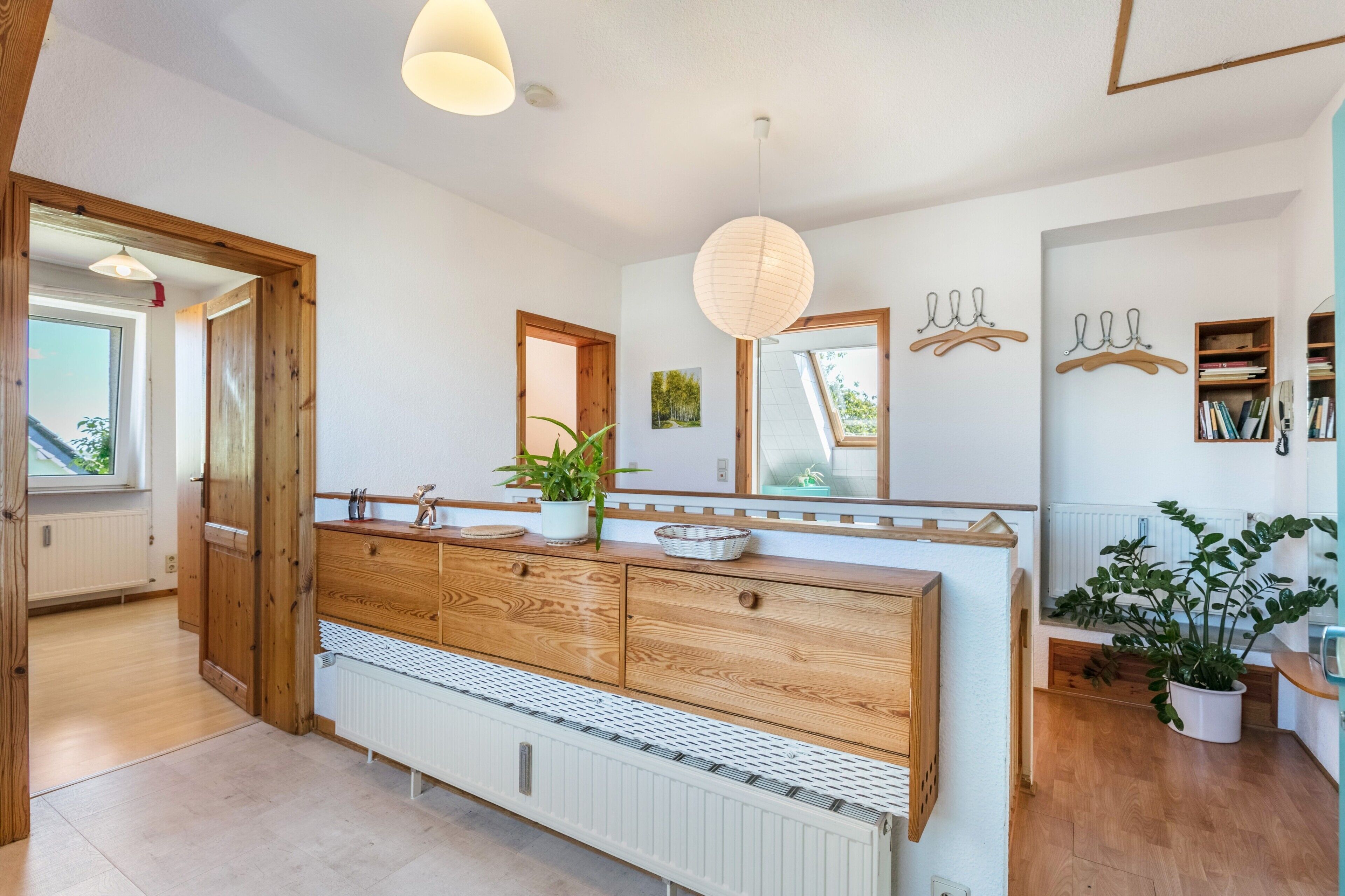Une salle de bain moderne avec un meuble-lavabo en bois, un grand miroir et une plante en pot.