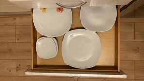 Ein Küchenschrank mit vier weißen Tellern und einer kleinen Schüssel.
