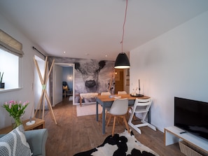 A modern living room with a large wall mural, a dining area, and a TV.