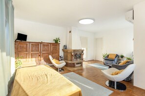 A modern living room with a sofa, a chair, a fireplace, and a television. - Holiday Apartment 'The Green Park Nest Frankfurt' with Terraces, WiFi & Air Conditioning (Friedrichsdorf)