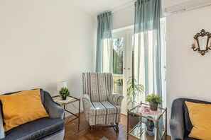 A living room with a striped armchair, two sofas, a glass coffee table, and a potted plant. - Holiday Apartment 'The Green Park Nest Frankfurt' with Terraces, WiFi & Air Conditioning (Friedrichsdorf)