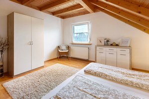 A bedroom with a sloped ceiling, a window, a radiator, a bed, a wardrobe, and a chair. - Sunny Apartment with Balcony and Wi-Fi (Küssaberg)
