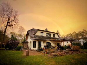A two-story house with a tiled roof, a front porch, and a garden area.