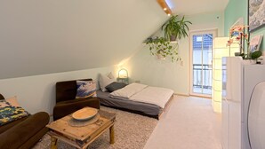 Een gezellige kamer met een bed, een sofa, een klein tafeltje en een potplant.