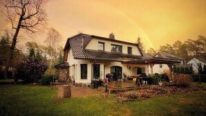 Een tweelaags huis met pannendak, een veranda en een tuin.