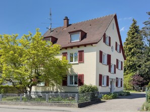 A two-story house with a sloped roof, multiple windows with shutters, and a visible chimney.