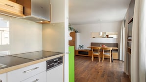 A modern kitchen with a dishwasher, a wooden countertop, and a dining area with a bench and table. - Obst- und Ferienhof Lehle – Apartment Jonagold with Shared Terrace, Garden & Wi-Fi (Immenstaad am Bodensee)
