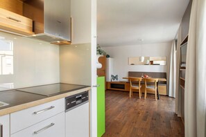 A modern kitchen with a dishwasher, a wooden countertop, and a dining area with a bench and table.