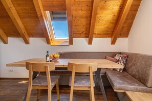 A loft-style room with a wooden ceiling, a skylight, a wooden dining table with chairs, a sofa, and a small fruit bowl. - Apartment 'Wohnung Elstar' with Shared Terrace, Shared Garden and Wi-Fi (Immenstaad am Bodensee)