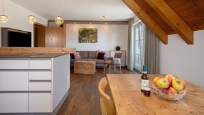 A modern kitchen with wooden beams, a dining table with apples, and a sofa in the living area.