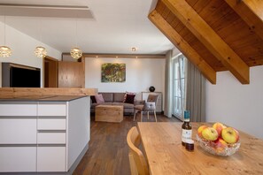 A modern kitchen with wooden beams, a dining table with apples, and a sofa in the living area. - Apartment 'Wohnung Elstar' with Shared Terrace, Shared Garden and Wi-Fi (Immenstaad am Bodensee)