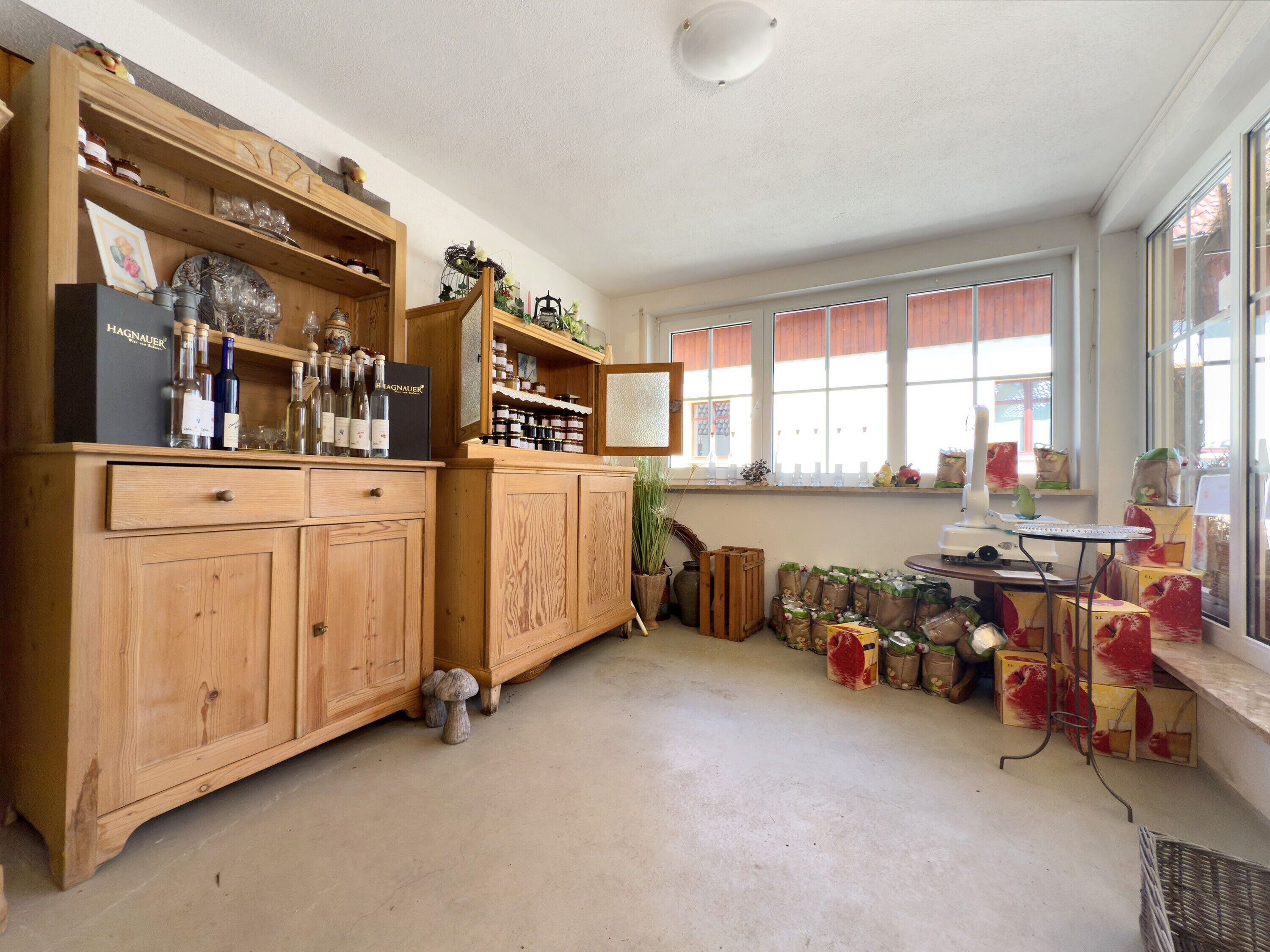Ein Zimmer mit Holzschränken, einem Fenster mit roten Jalousien und diversen Gegenständen auf Regalen.