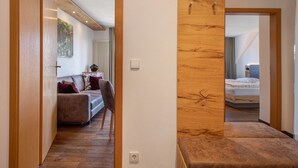 A hallway with a wooden accent wall, a sofa with cushions, a bed with a white duvet, and a radiator.