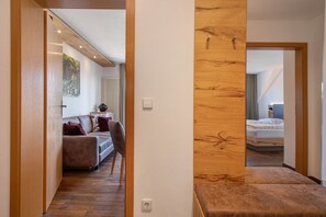 A hallway with a wooden accent wall, a sofa with cushions, a bed with a white duvet, and a radiator. - Apartment 'Wohnung Elstar' with Shared Terrace, Shared Garden and Wi-Fi (Immenstaad am Bodensee)