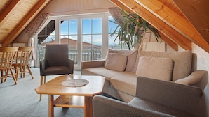 A cozy attic room with a wooden ceiling, a sofa, a table, and a chair. - Obst- und Ferienhof Lehle - Apartment Bodensee with Shared Terrace, Garden and Wi-Fi (Immenstaad am Bodensee)