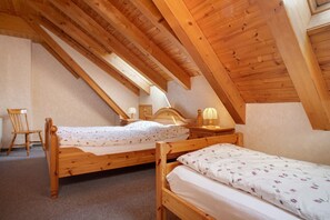Une chambre à coucher avec deux lits en bois, une chaise et une table de chevet avec une lampe.