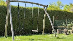 A wooden swing set in a garden with a hedge and a fence in the background. - Obst- und Ferienhof Lehle - Apartment Bodensee with Shared Terrace, Garden and Wi-Fi (Immenstaad am Bodensee)